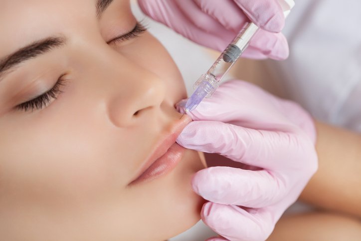 The doctor cosmetologist makes Lip augmentation procedure of a beautiful woman in a beauty salon